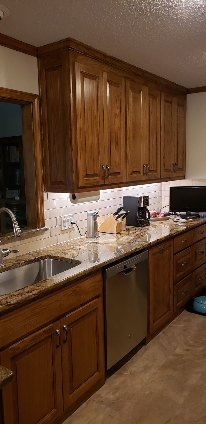 A kitchen with wooden cabinets, granite counter tops, a sink, and a dishwasher.