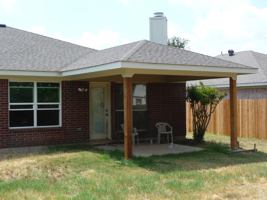 A brick house with a covered patio in the backyard