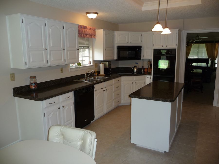 A kitchen with white cabinets and black counter tops