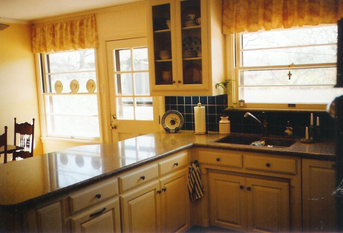 A kitchen with white cabinets and black counter tops