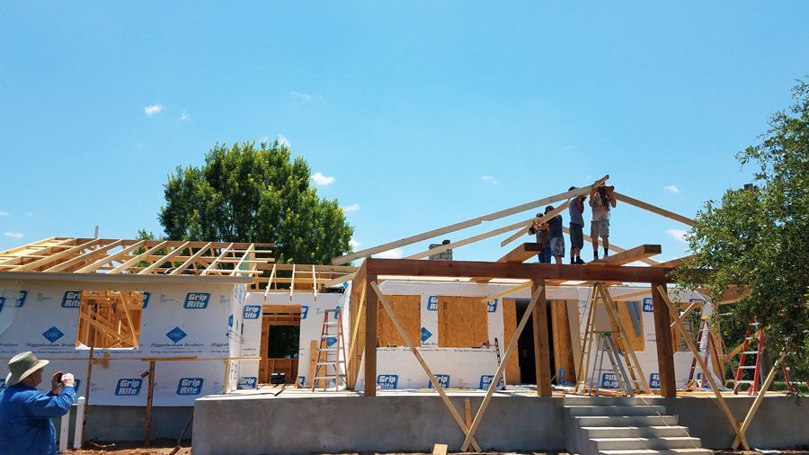 A group of people are working on a house under construction.