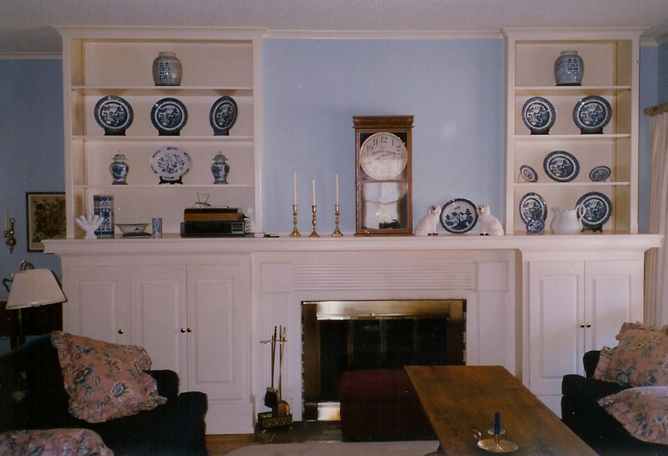 A living room with a fireplace and shelves filled with blue and white vases
