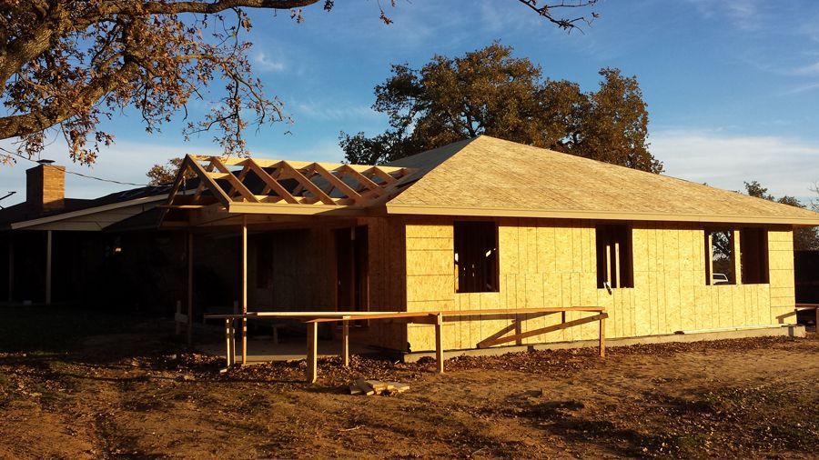 A house is being built in a field with a tree in the background.