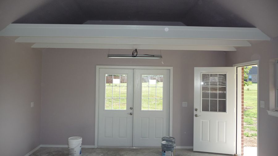 An empty room with white doors and a bucket on the floor
