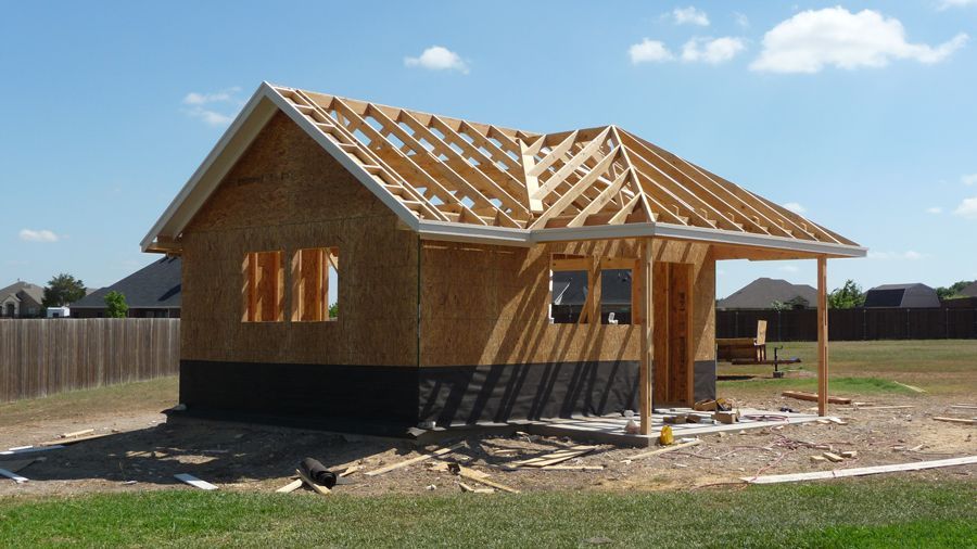 A small wooden house is being built in a backyard