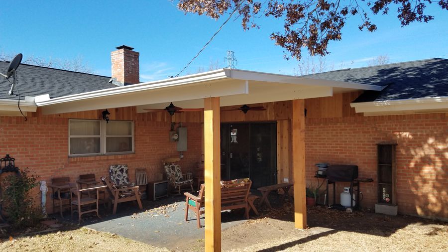 A brick house with a covered patio in front of it.