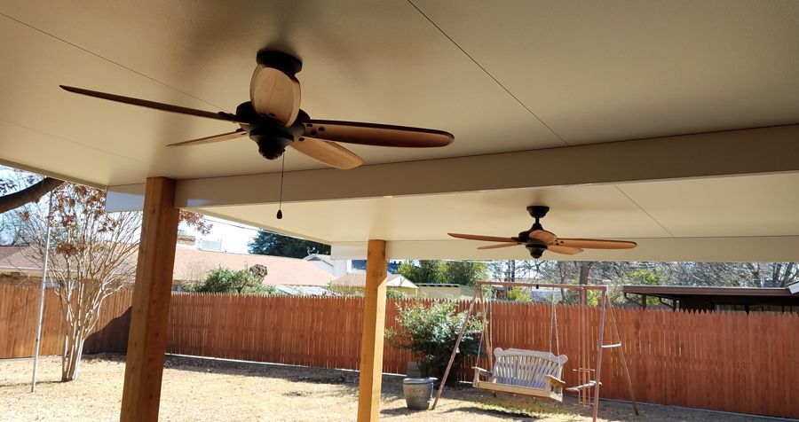 Two ceiling fans are hanging from the ceiling of a patio.
