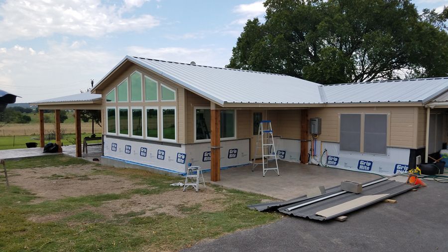 A house with a white roof and a lot of windows is being built.