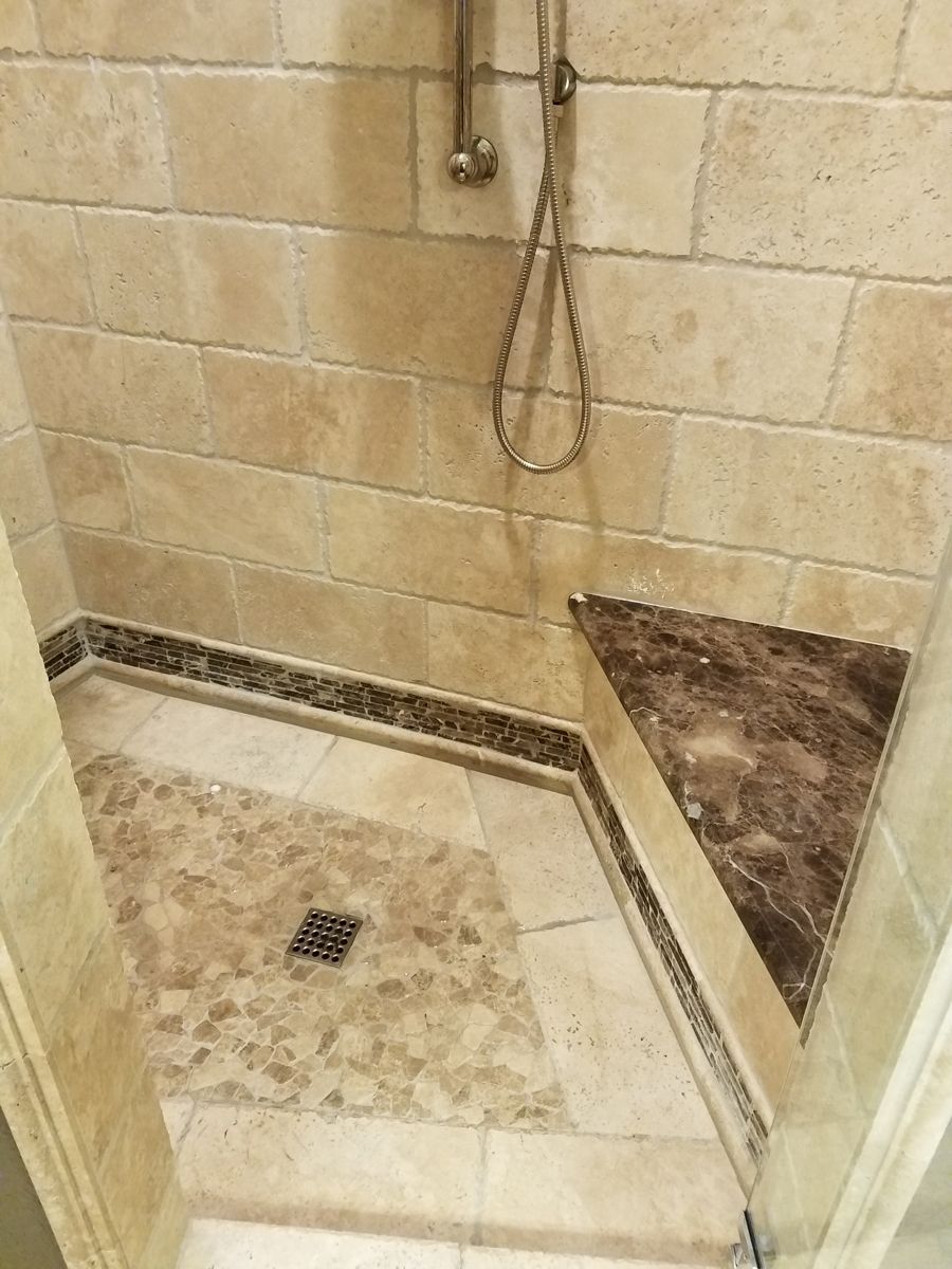 A bathroom with a walk in shower and a tiled floor.