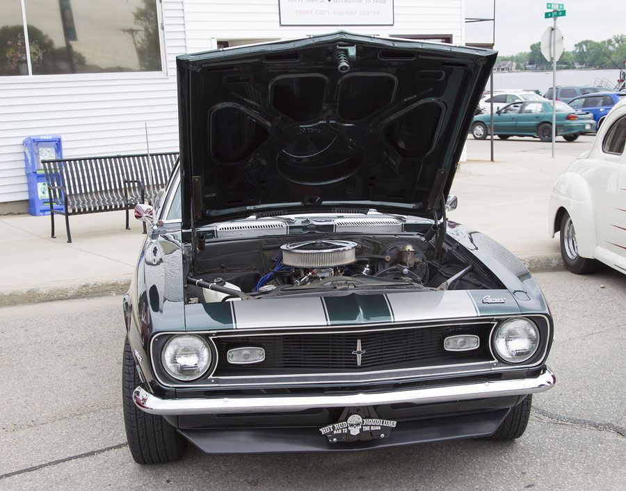 A black car with the hood up is parked on the street