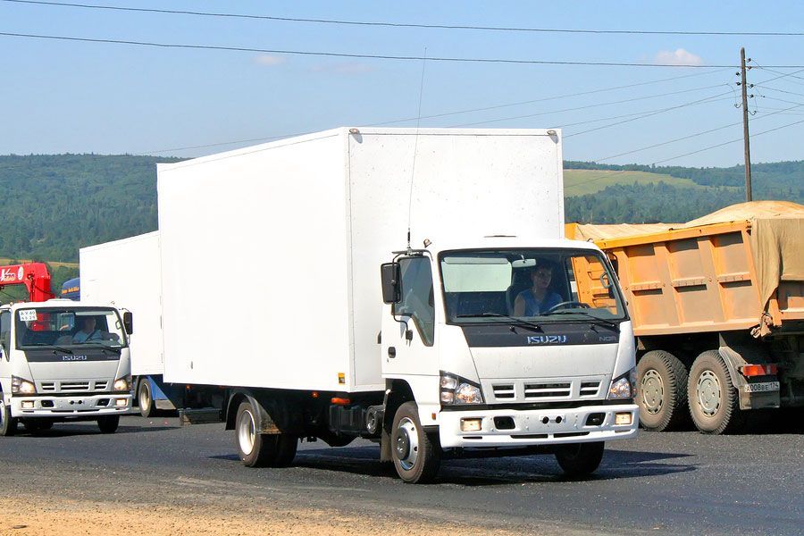 A white truck is driving down the road next to a dump truck