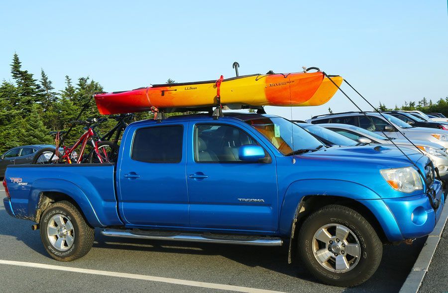 A blue truck with two kayaks on top of it