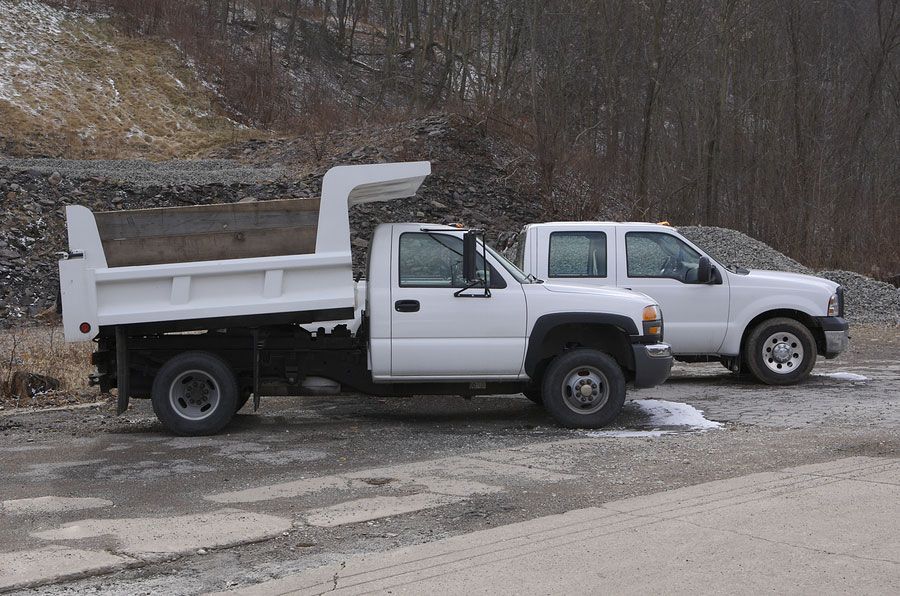 Two white dump trucks are parked next to each other