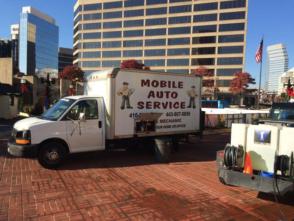 A mobile auto service truck is parked in front of a building