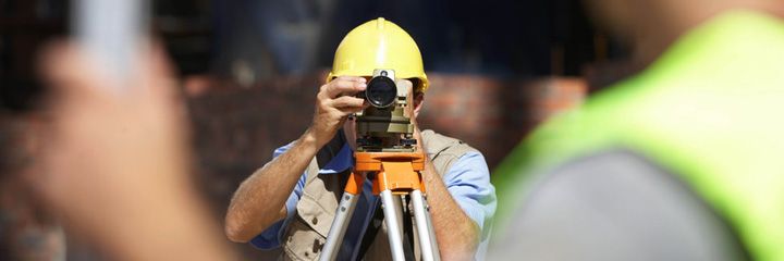 Man  in hard hat using a surveying tool