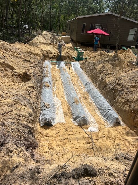 Construction site, trenches with covered drainage lines, workers, and house