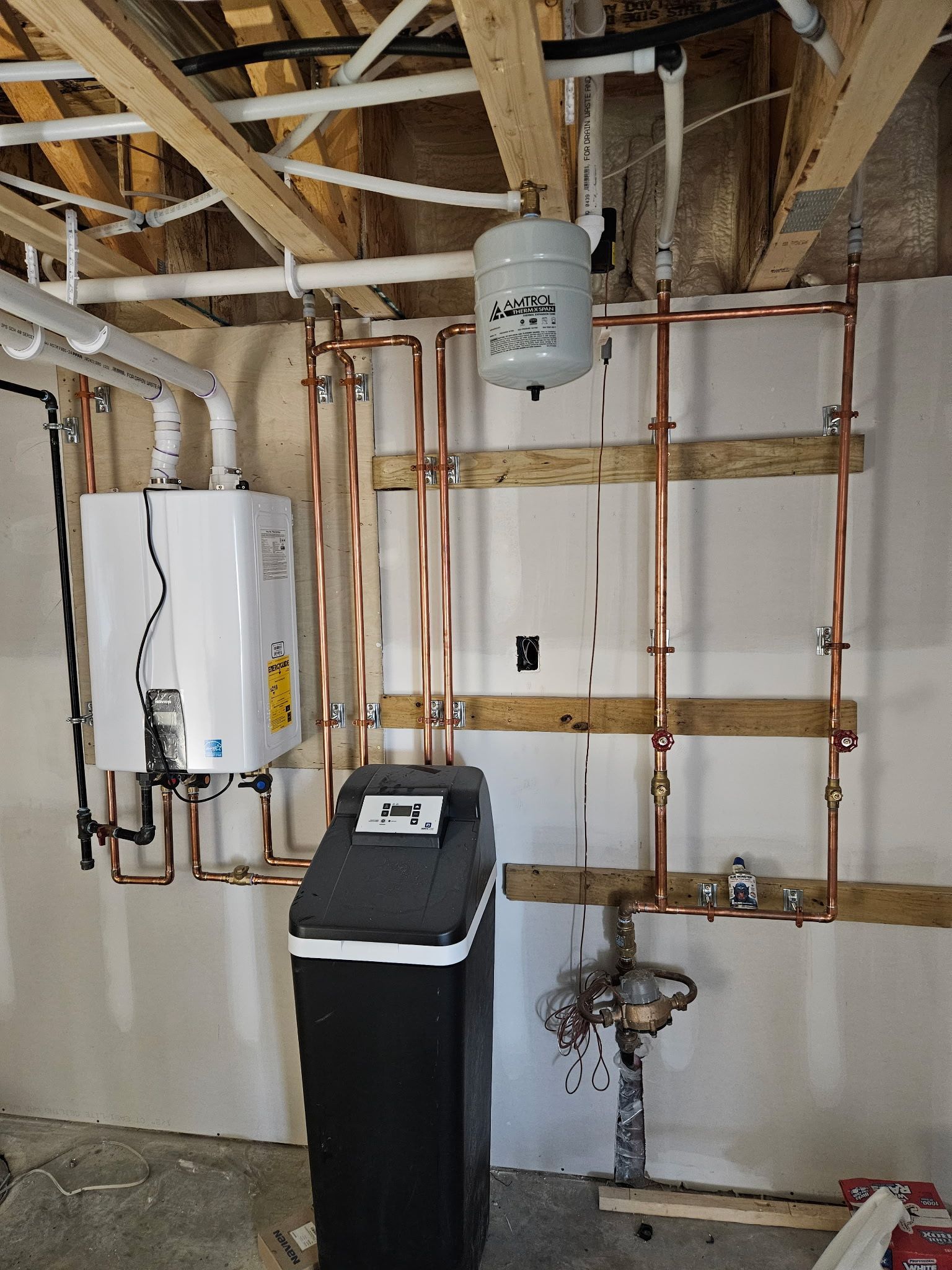 Plumbing system with copper pipes, water heater, water softener, and expansion tank in a basement.