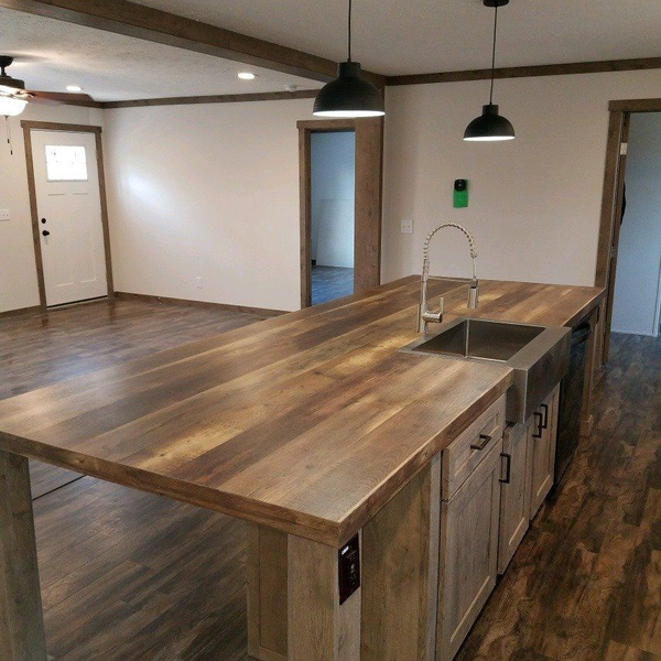 Kitchen with wood island, sink, pendant lights, and wooden cabinets.