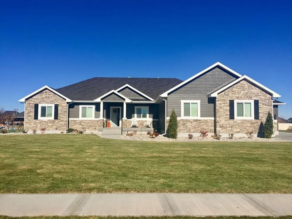 Ranch-style house with gray siding and stone accents on a sunny day with a blue sky.