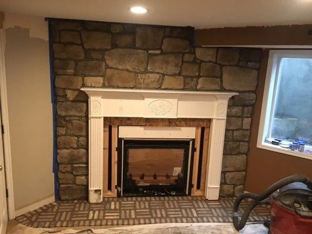 Fireplace with stone facade, white mantel, and brick hearth.