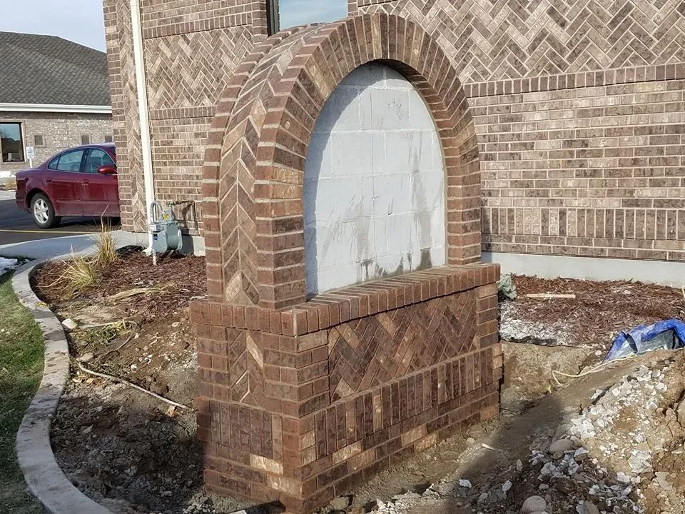 Brick arched structure in front of a brick building.