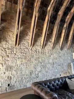 Stone wall with wooden beams, curved ceiling, and a leather sofa.