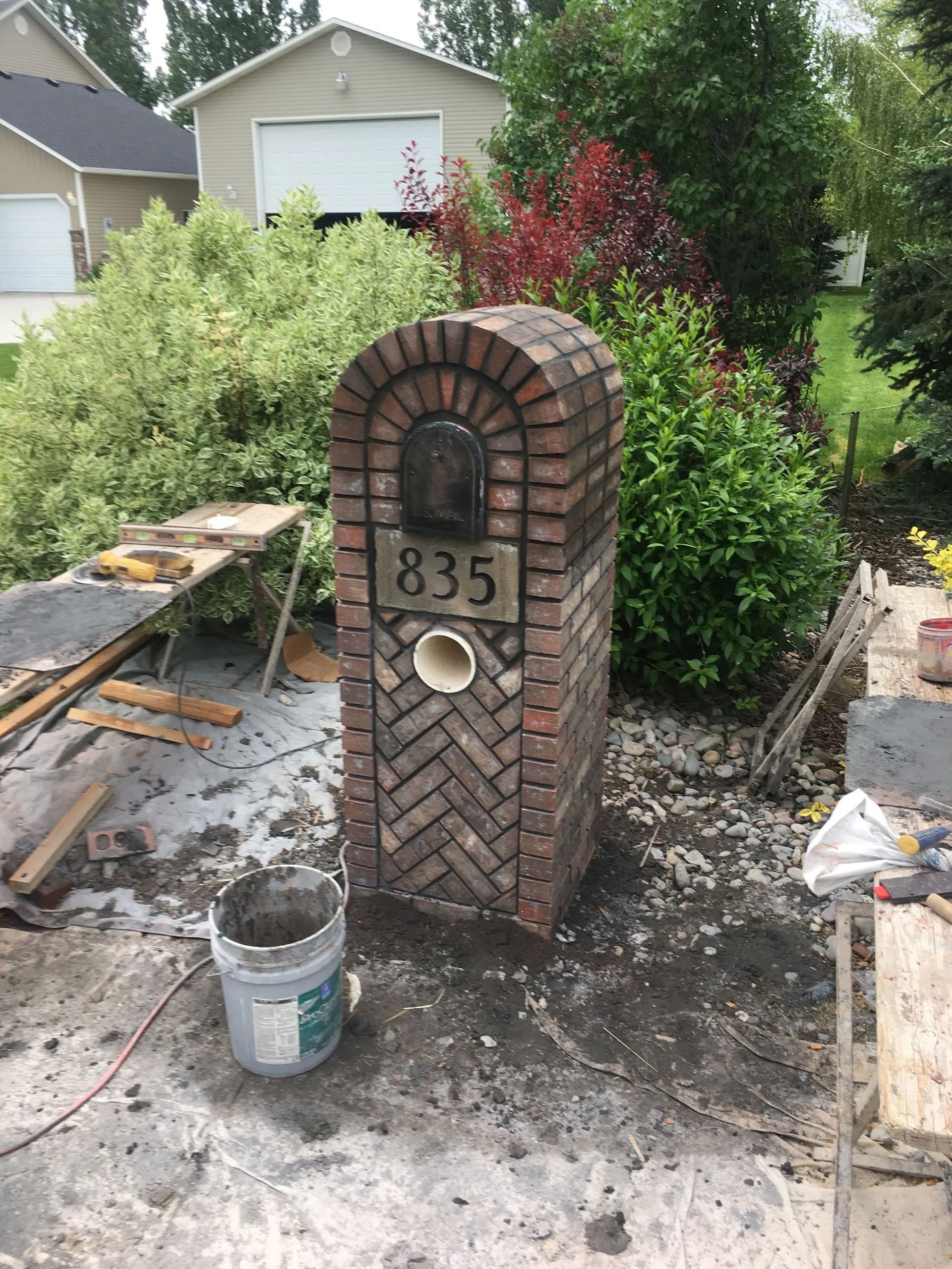 Brick mailbox with address 835, set in a yard, construction debris around.