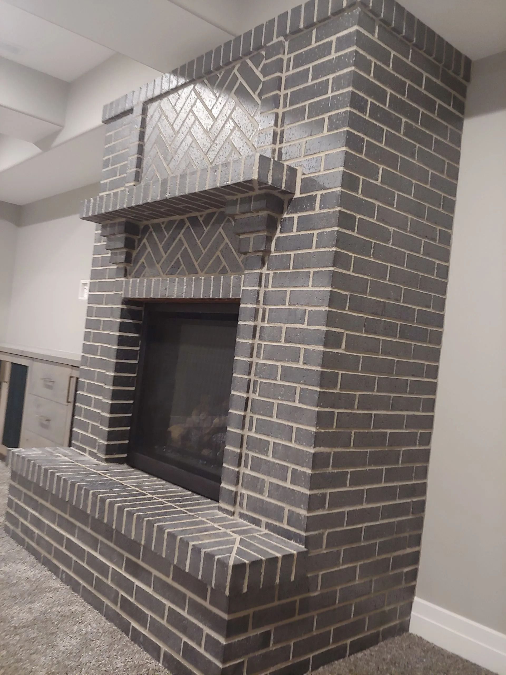 Dark brick fireplace with decorative chevron pattern above the firebox.