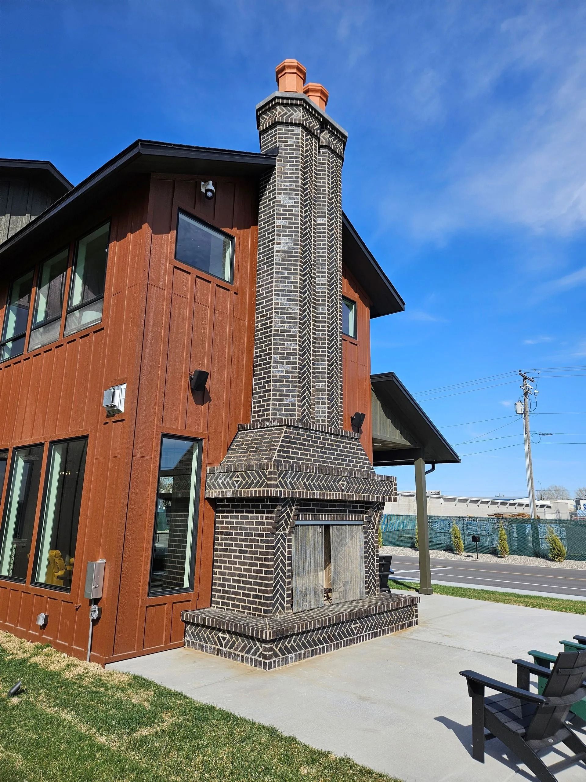 Brick chimney and fireplace on a brown building with windows, sunny day.