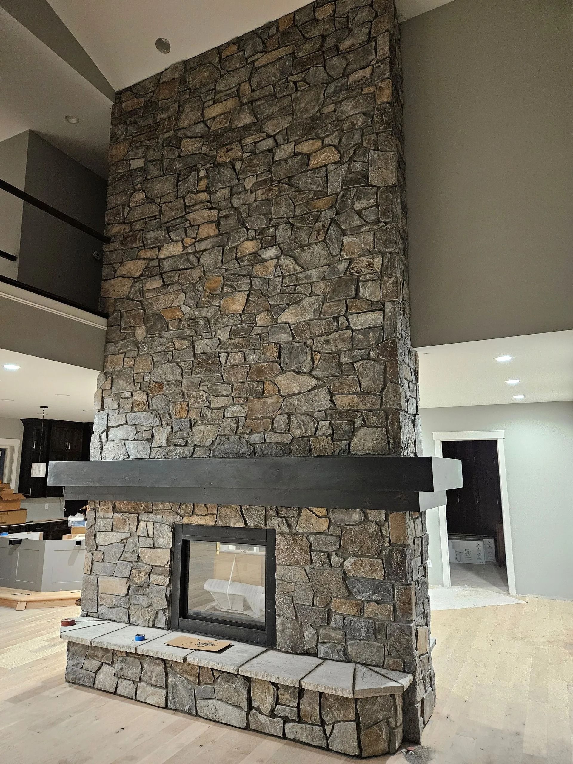 Stone fireplace with dark mantle, built-in bench, and rectangular firebox; light-colored room.