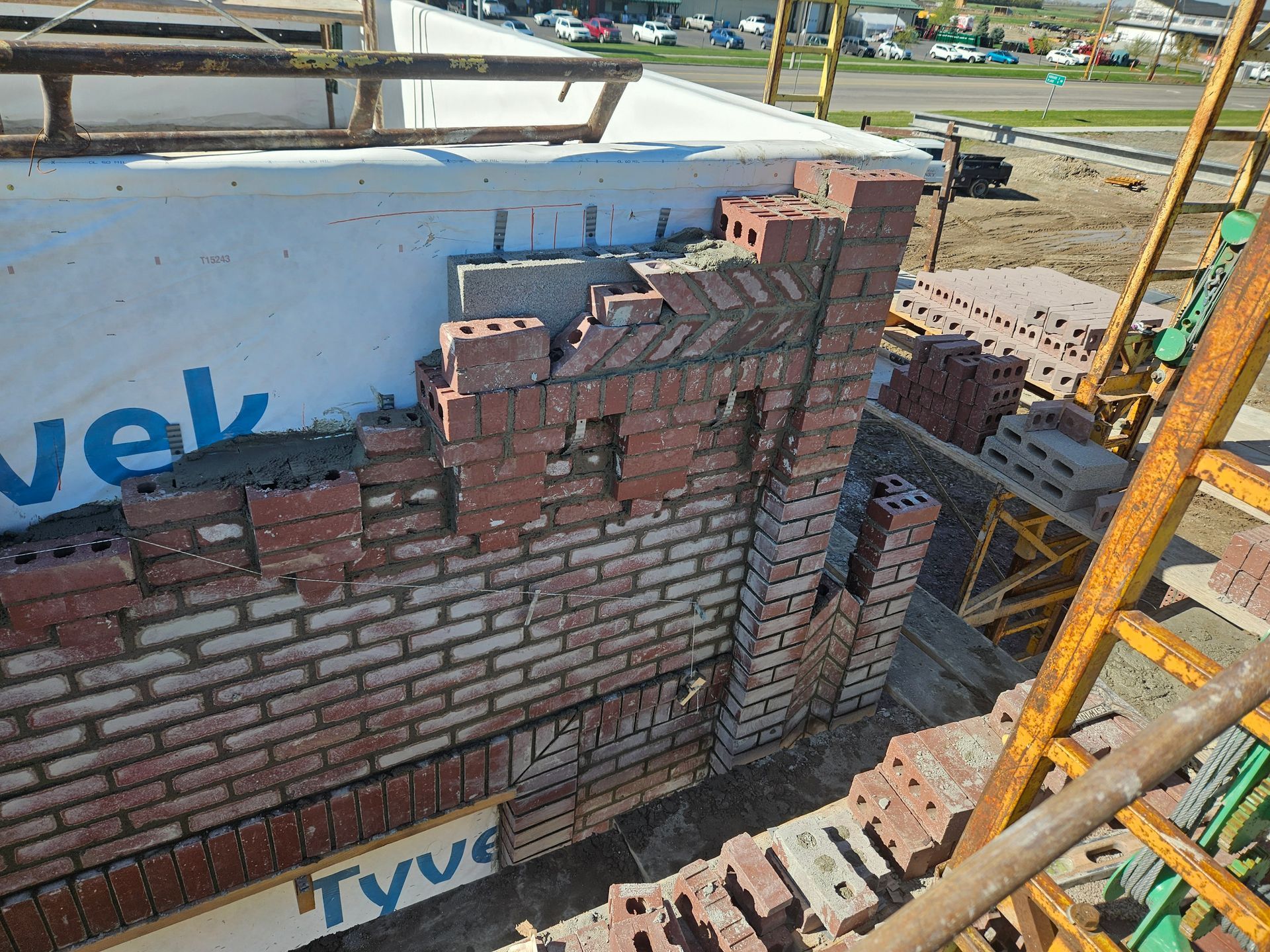 Brick construction of a building exterior, red bricks being laid on a wall, construction site.
