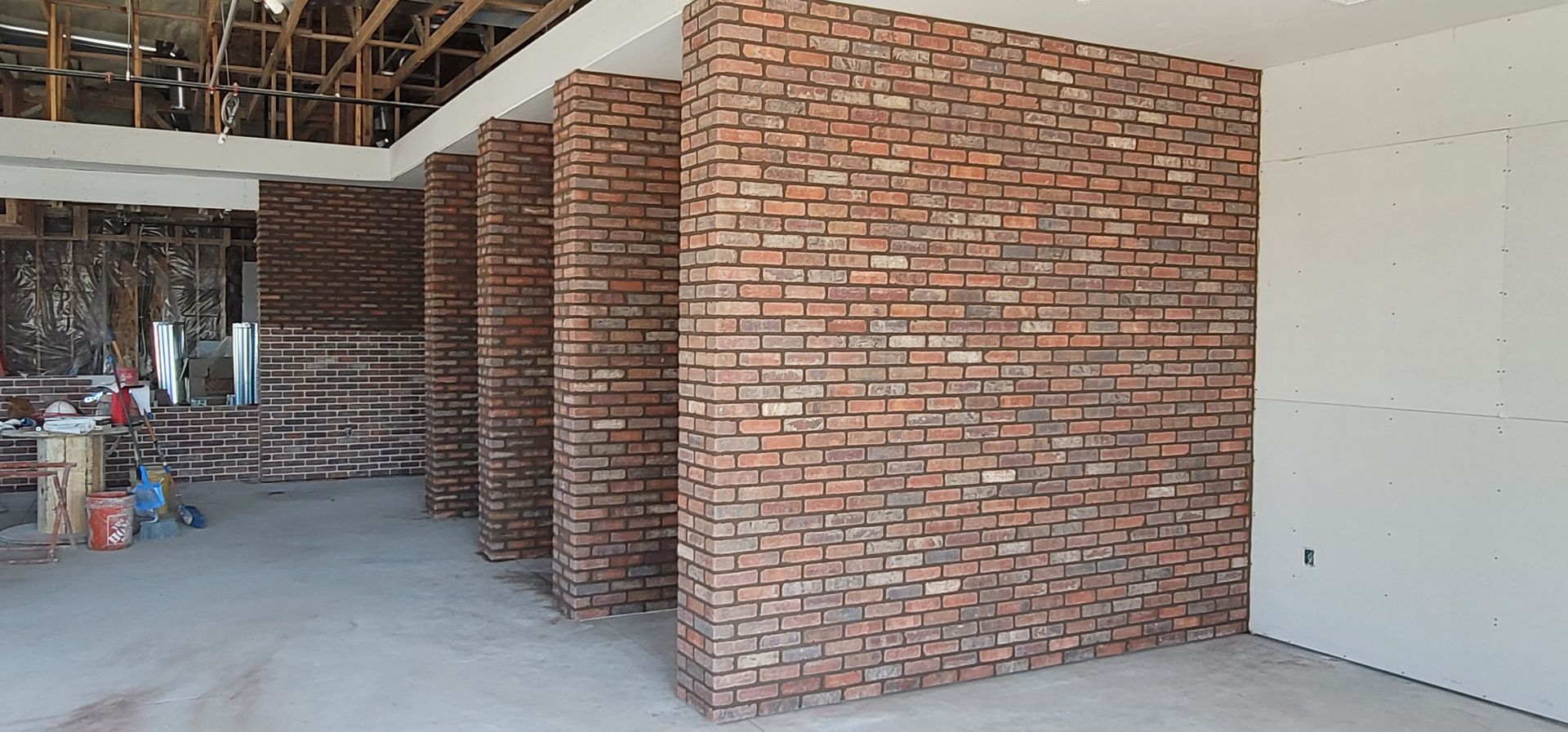 Interior construction: Brick accent walls and columns. Drywall on the right side. Open ceiling and concrete floor.