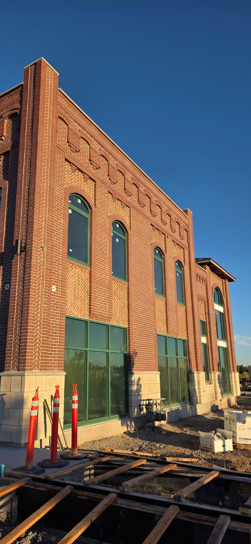 Brick building under construction with arched windows and green glass.