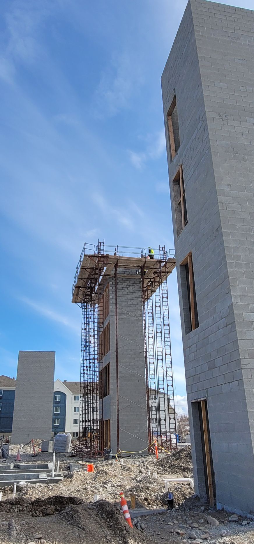 Construction site with scaffolding around tall brick structures against a blue sky.