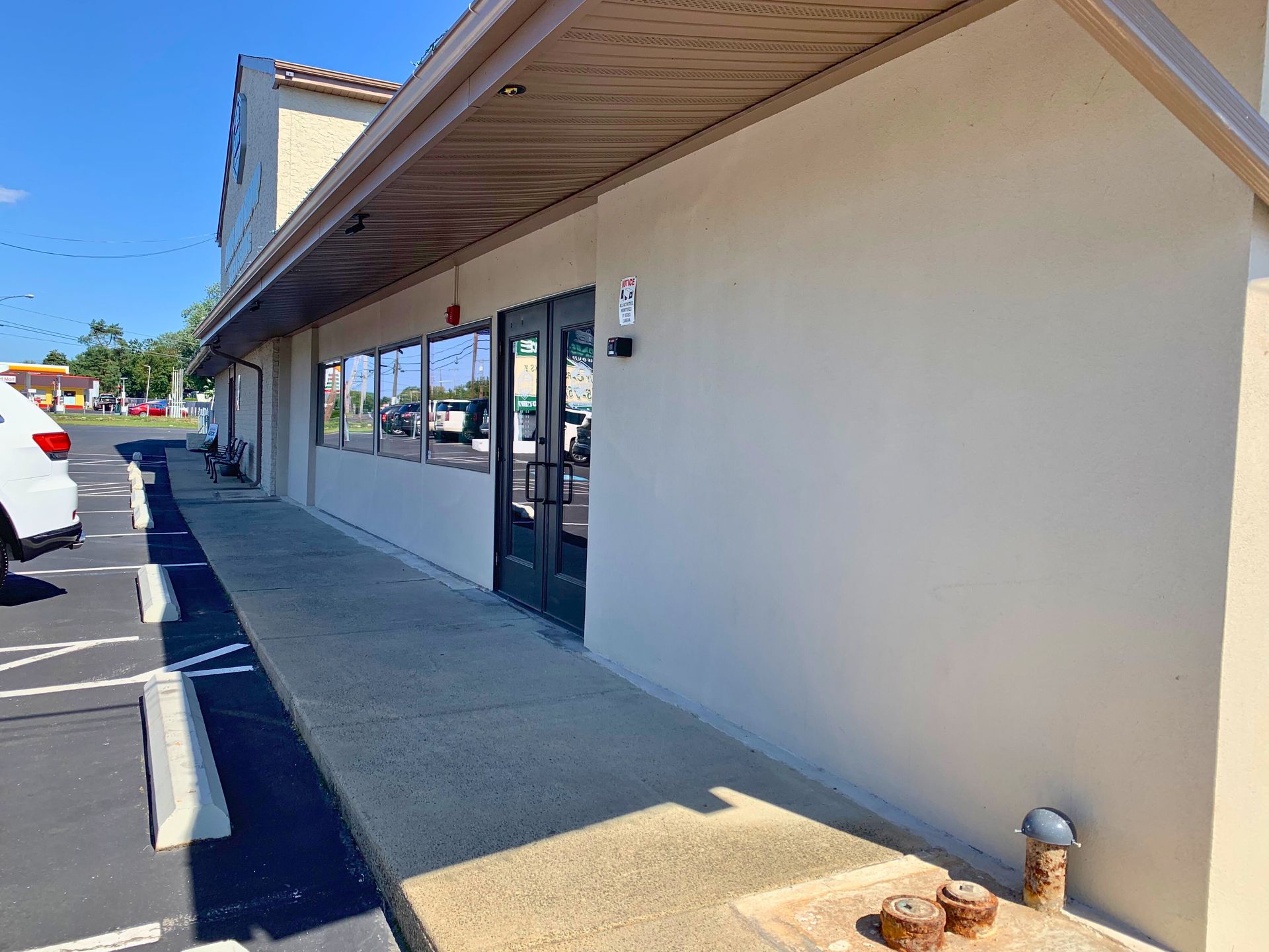 Exterior of a commercial building with a tan facade, windows, and a walkway.