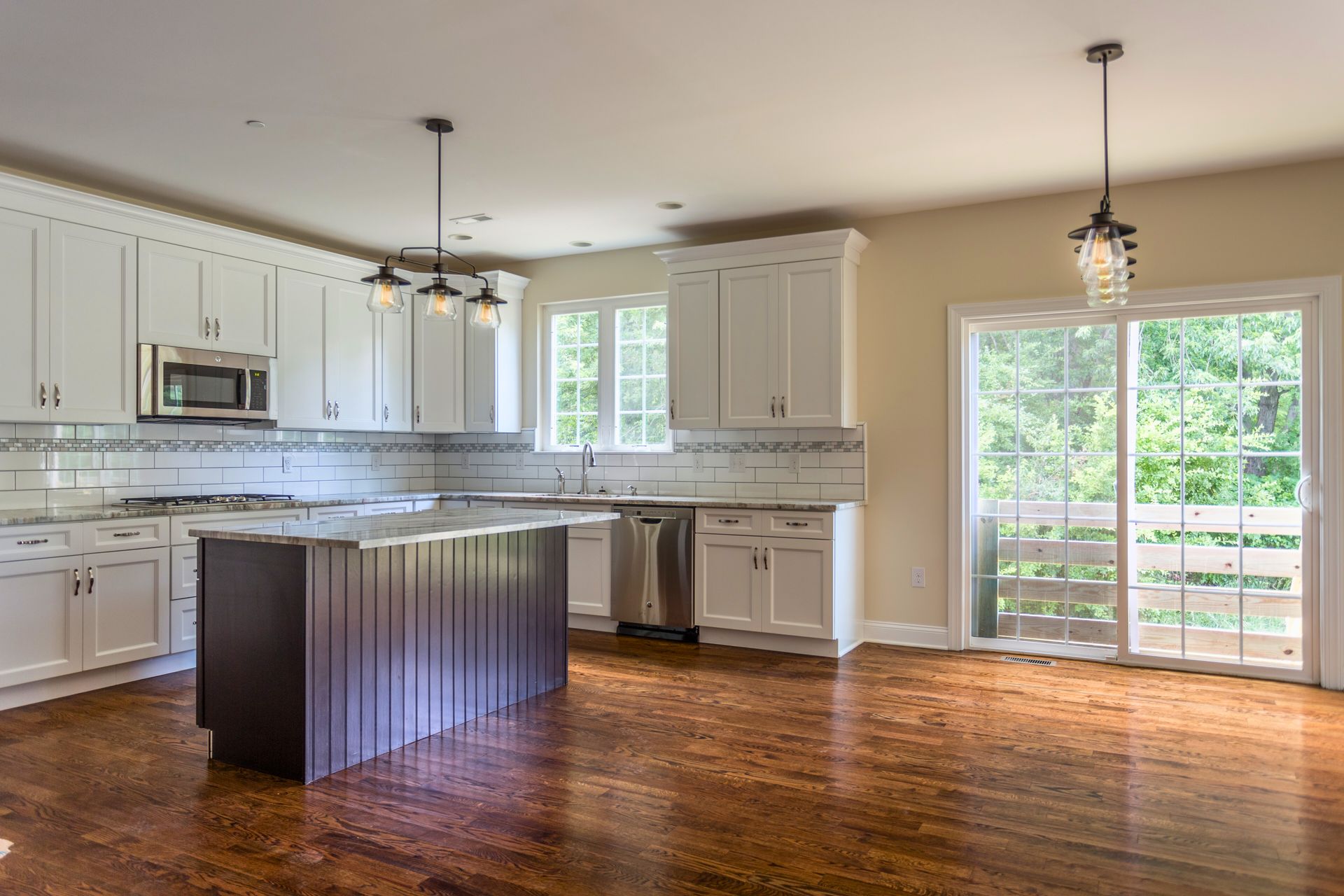 Bright kitchen with white cabinets, dark island, and a sliding glass door.