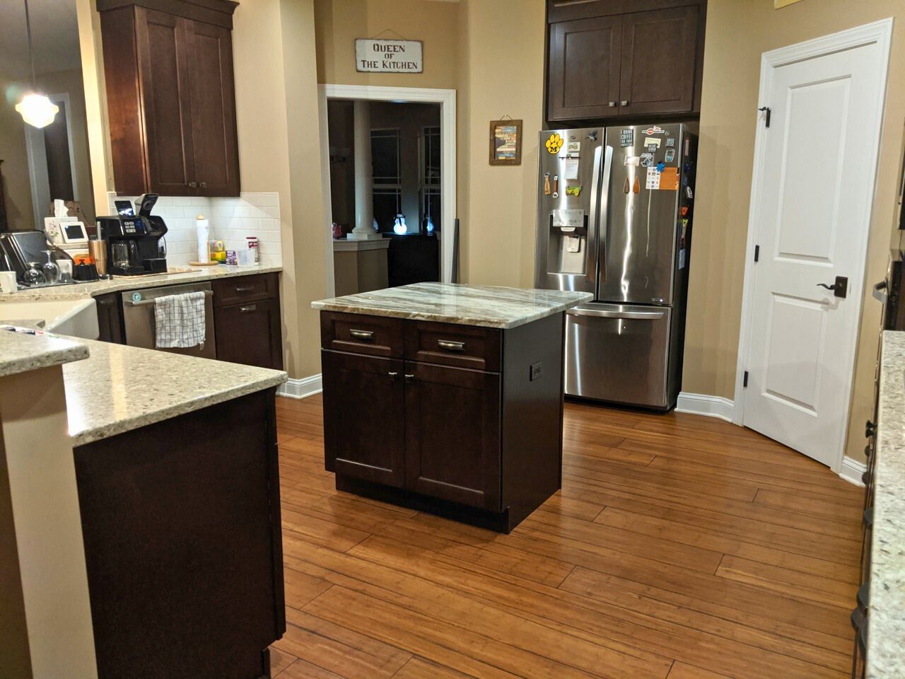 Kitchen with dark brown cabinets, granite countertops, stainless steel refrigerator, and a centered island.
