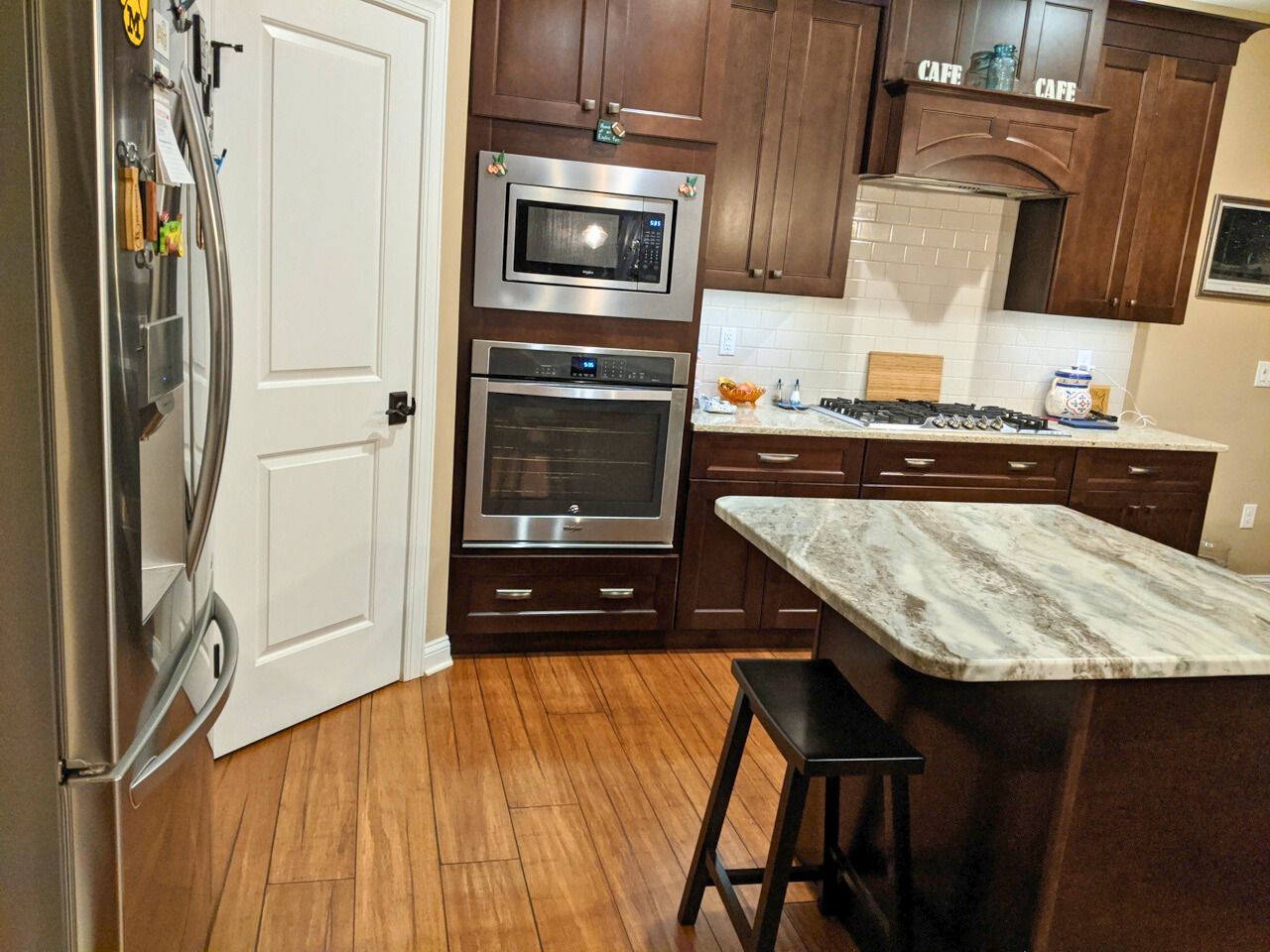 Kitchen with wood cabinets, stainless steel appliances, granite island, and hardwood floors.