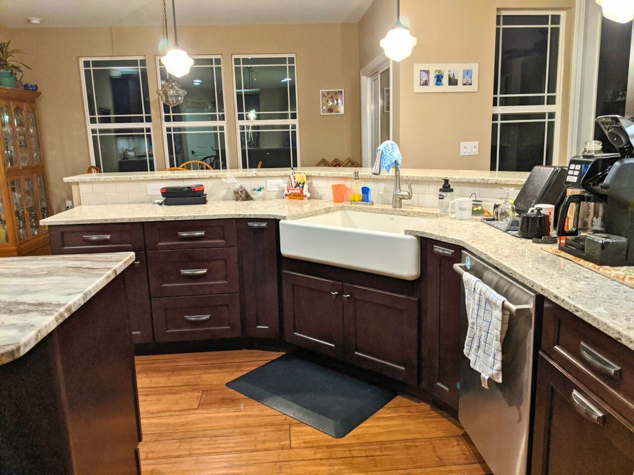 Dark wood kitchen cabinets with light countertops, farmhouse sink, and windows.