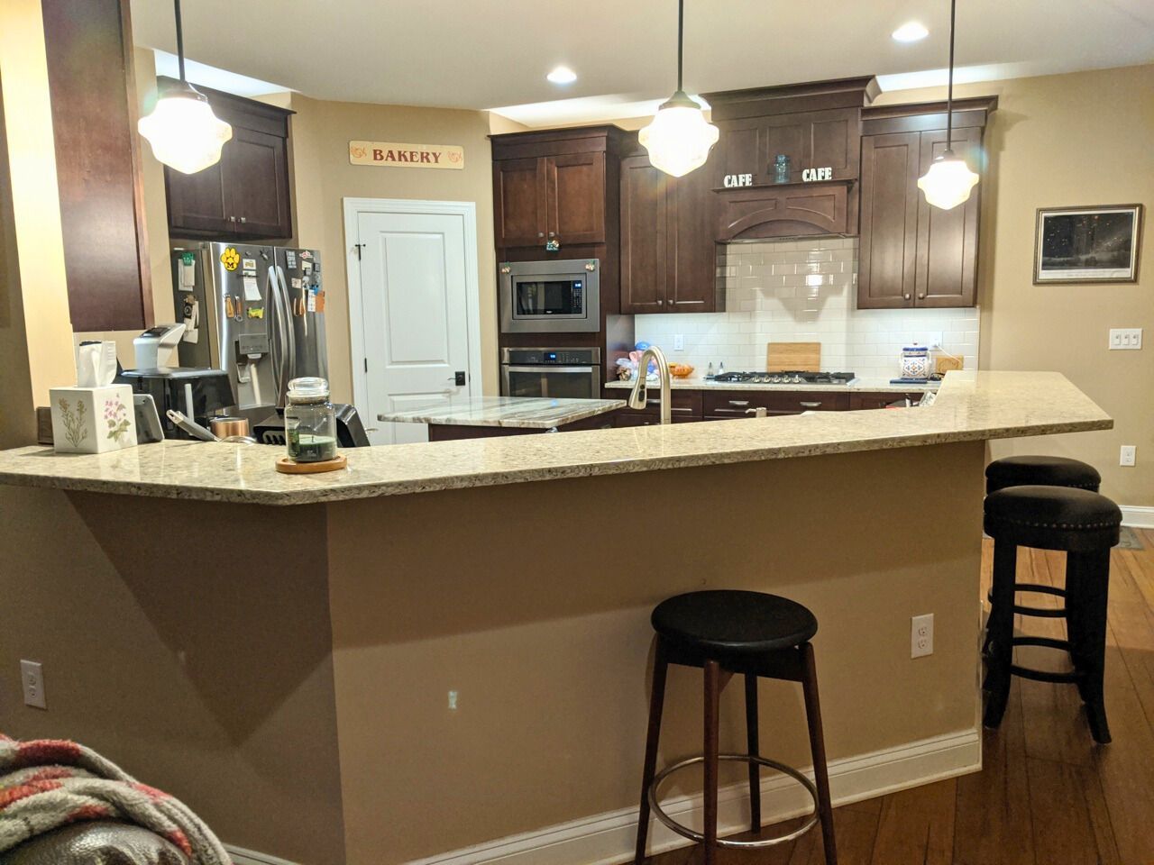 Kitchen with dark wood cabinets, granite countertop, and three pendant lights.
