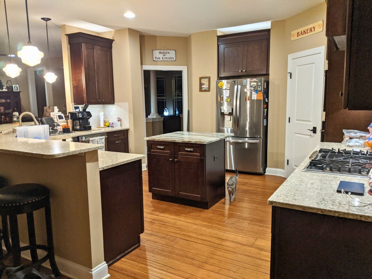 A kitchen with dark brown cabinets, stainless steel appliances, and a wooden floor.