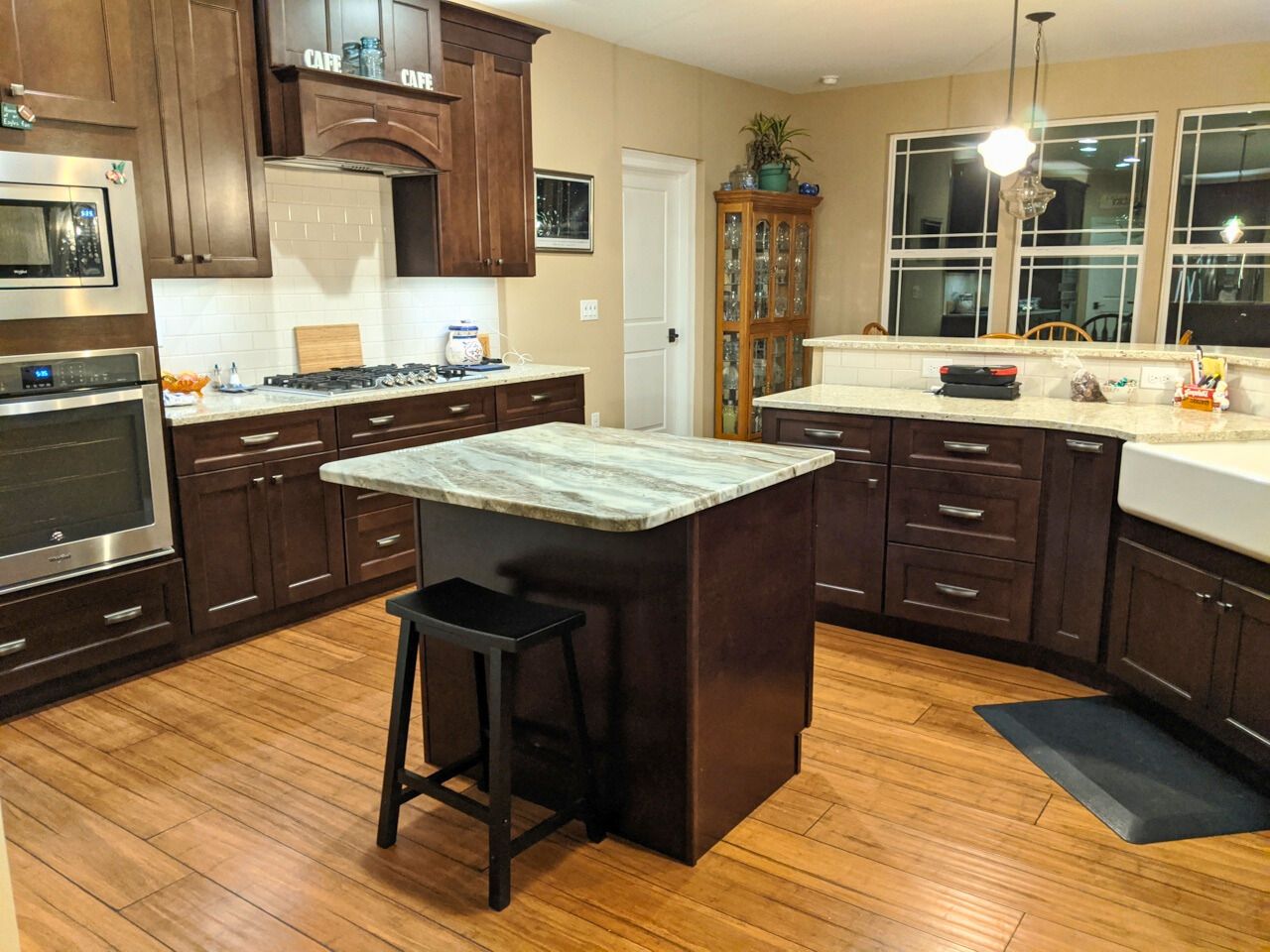 Kitchen with dark wood cabinets, a granite island, and light wood floors.