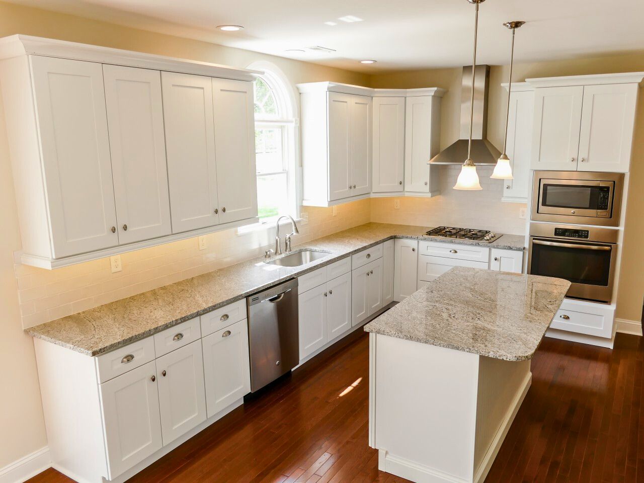White kitchen with granite countertops, stainless steel appliances, and an island.