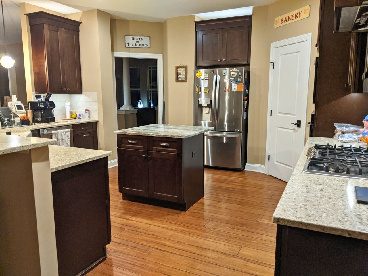 Kitchen with dark cabinets, stainless steel appliances, wood floors, and a center island.