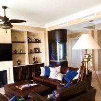 Living room with leather furniture, built-in shelves, aquarium, and a tripod floor lamp.