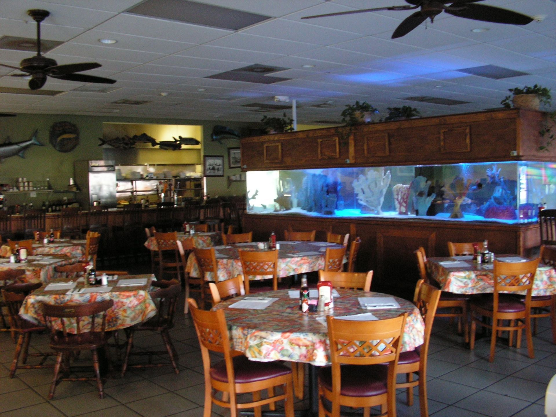 Restaurant interior with tables, chairs, and large aquarium; neutral colors.