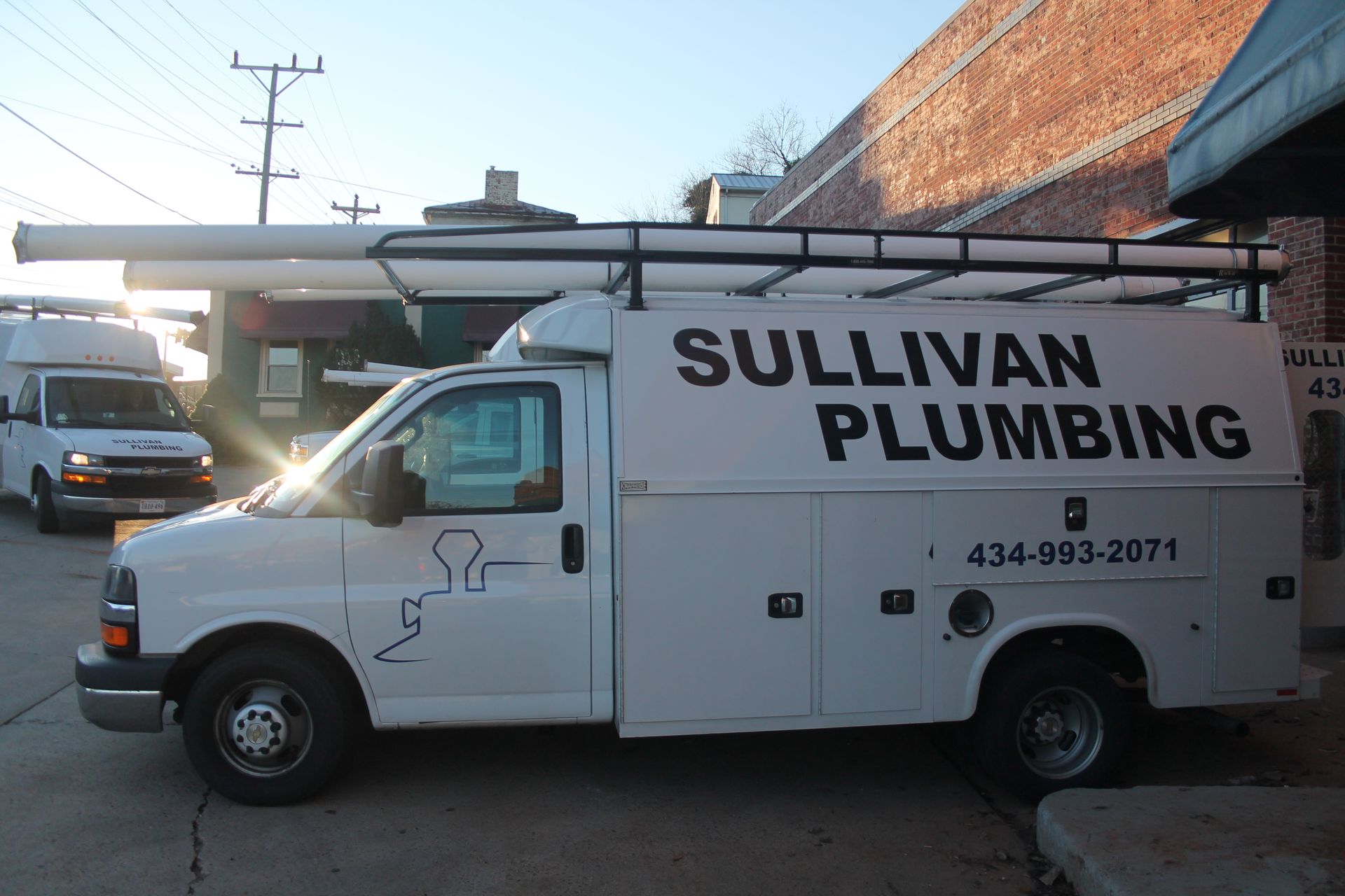 a white sullivan plumbing van is parked in front of a building
