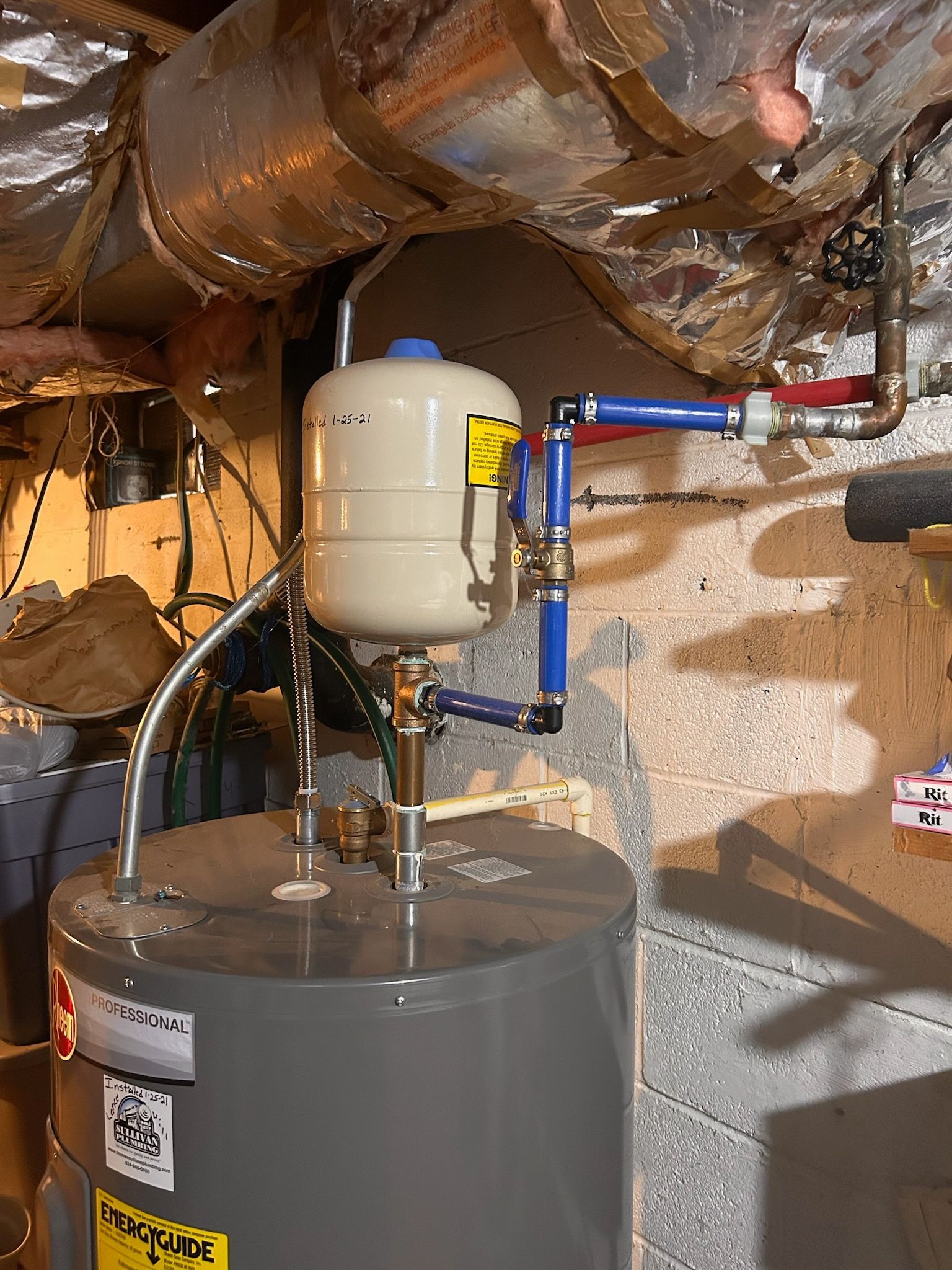 a water heater is sitting in a basement next to a wall .