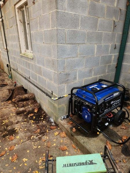 A blue generator is sitting on the side of a brick building.