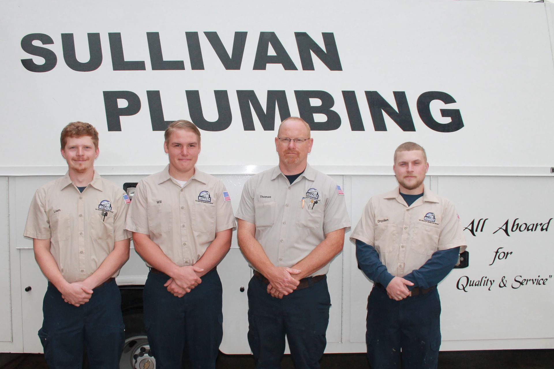 Four men standing in front of a truck that says sullivan plumbing